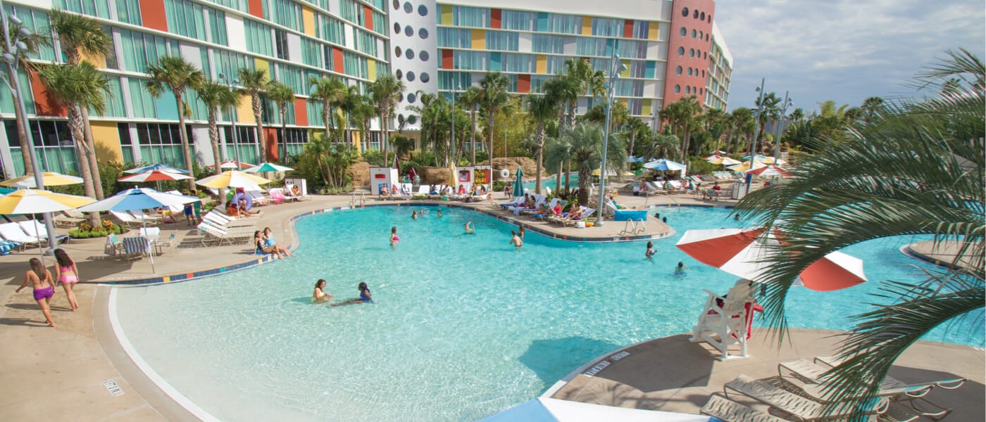 Visitantes do Cabana Bay Beach Resort no Universal Orlando nadam e relaxam no Lazy River Courtyard, onde uma piscina com entrada gratuita convida pessoas de todas as idades a se divertirem ao sol.