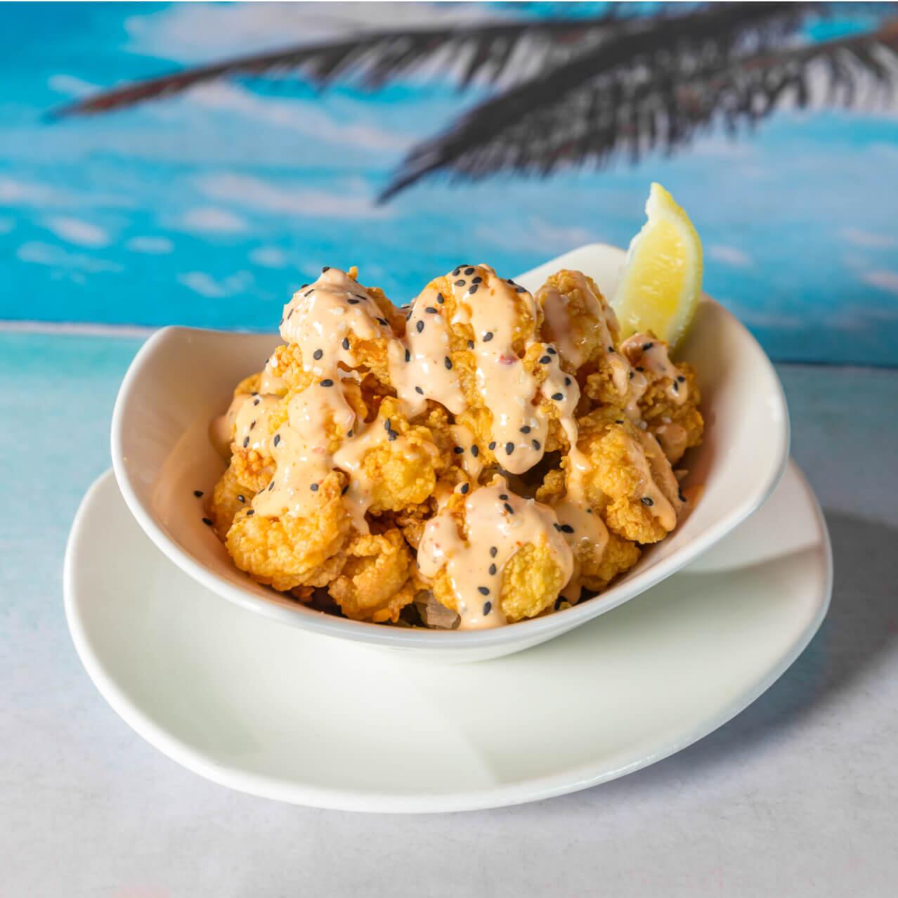 Um bowl de camarões fritos cobertos com um molho tentador e uma fatia de limão disposto em uma mesa do Jimmy Buffett's Margaritaville, um divertido restaurante no Universal CityWalk Orlando.