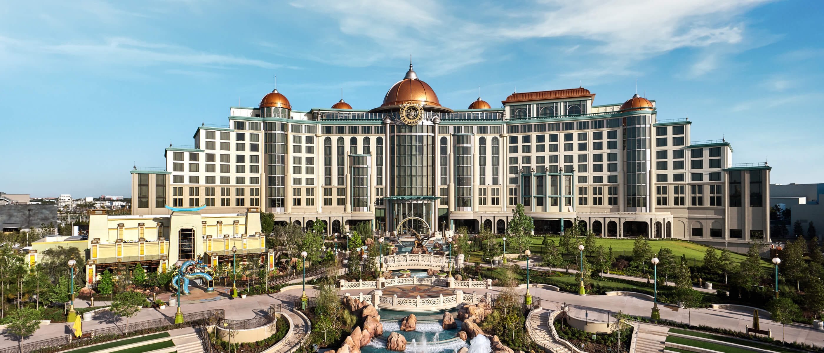 Vista do Universal Helios Grand Hotel, a Loews Hotel, com suas torres arredondadas que se erguem por trás de uma grande fonte de vários níveis e jardins paisagísticos.