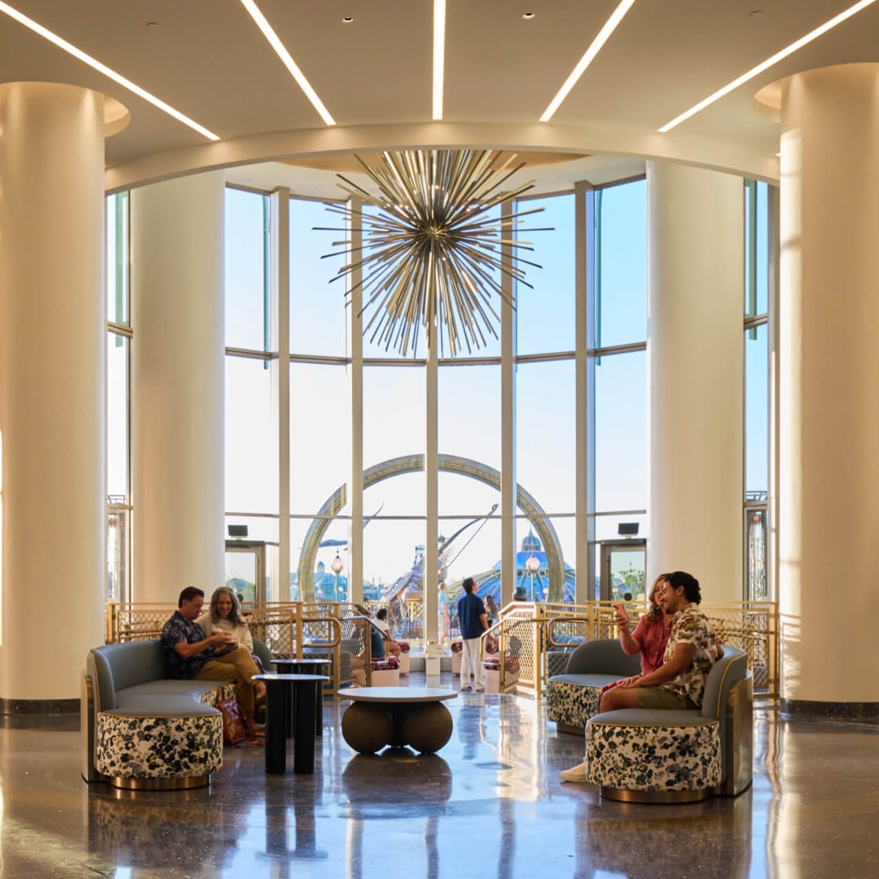 Lobby e lounge do Universal Helios Grand Hotel, a Loews Hotel, com amplo espaço para acomodação e vistas panorâmicas do Universal Epic Universe através de janelas do chão ao teto.