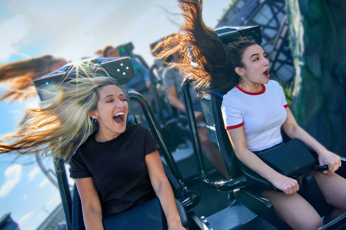 Two girls screaming as their roller coaster rounds a rocky curve.