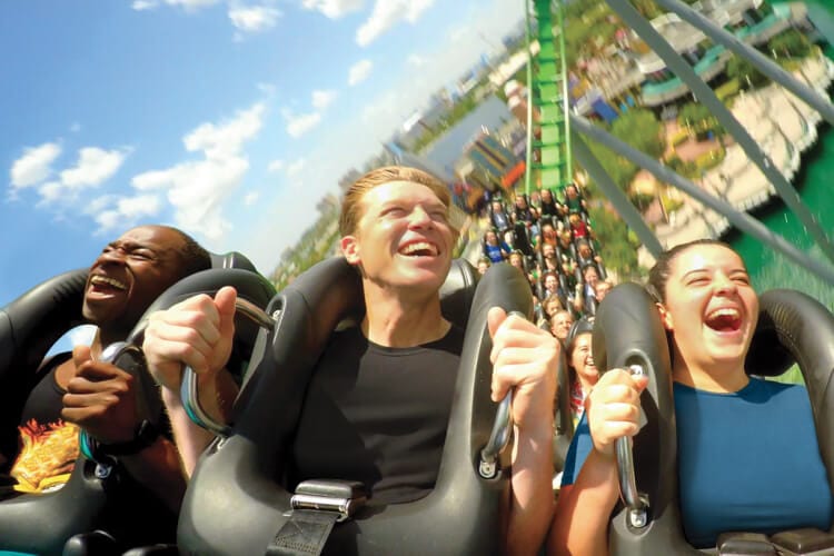 Close up of guests smiling while riding a roller coaster at Universal’s Islands of Adventure.