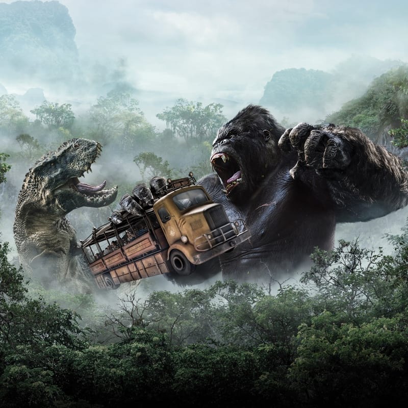King Kong segurando um ônibus escolar enquanto luta com um T-Rex