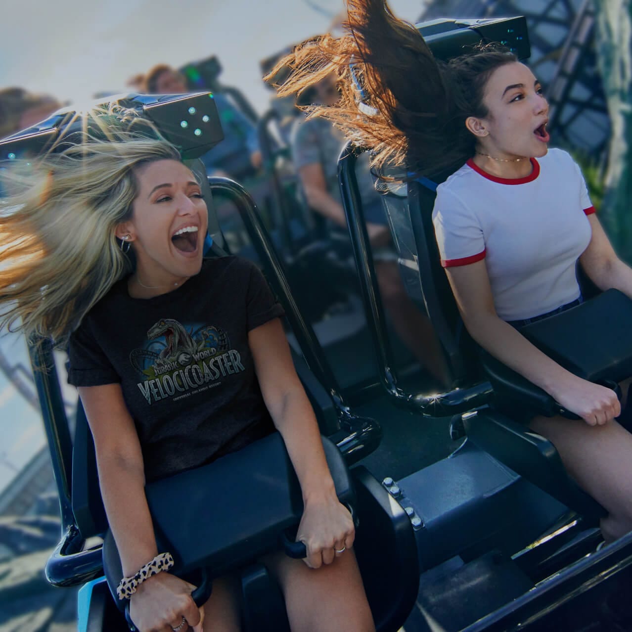 Two girls screaming as their roller coaster rounds a rocky curve.