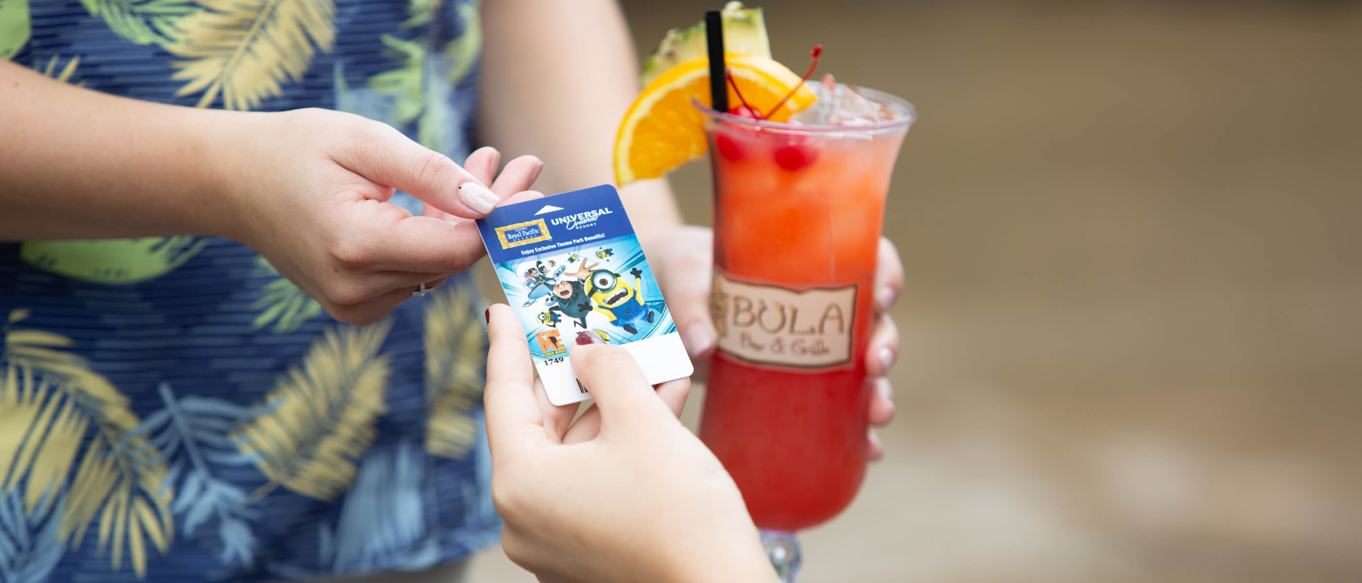 A guest at Loews Royal Pacific Resort hands her room key card to a server at Bula Bar & Grille to pay for a tropical drink.