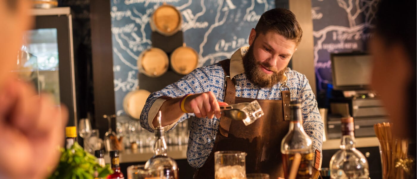 Bartender sorri enquanto prepara um drinque no Strong Water Tavern, um local para refeições no hotel do Universal Orlando, Loews Sapphire Falls Resort.