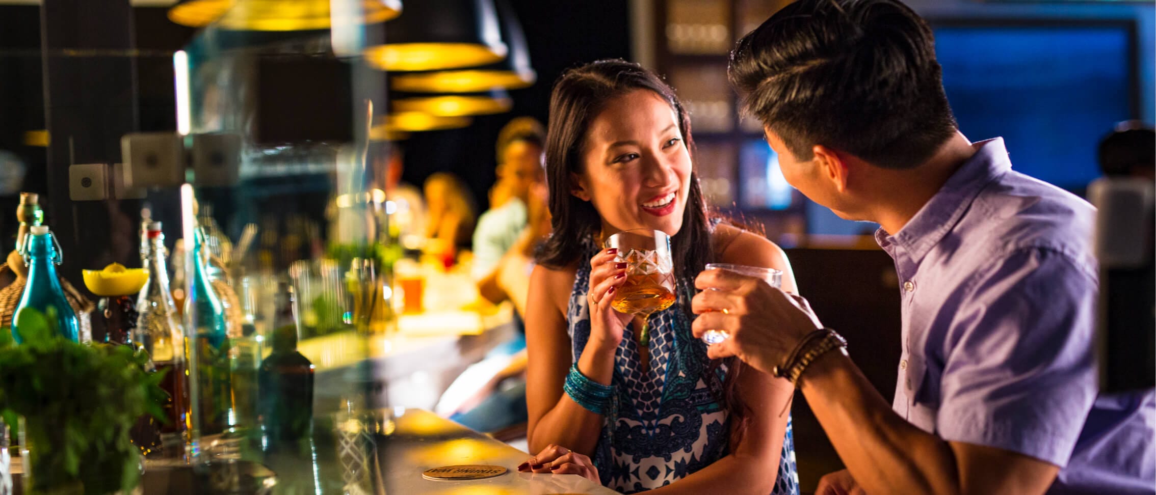Casal sorrindo e conversando enquanto bebe no Strong Water Tavern no Loews Sapphire Falls no Universal Orlando.