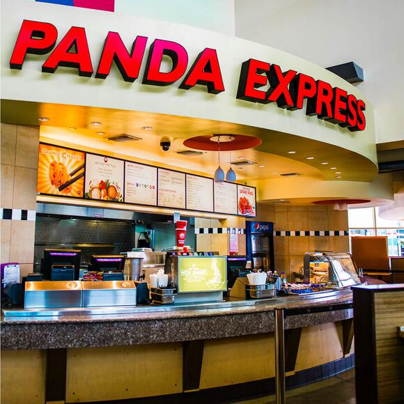 O interior do Panda Express no Universal CityWalk tem um grande guichê com cardápios iluminados e um logotipo com letras vermelhas.