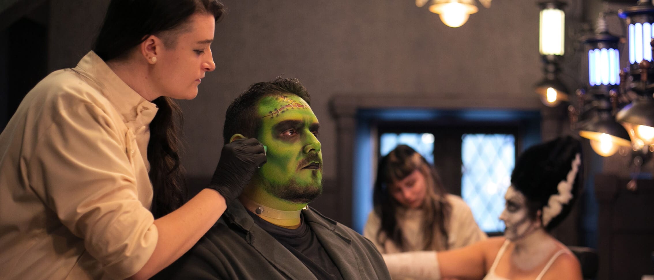 Um talentoso artista da Darkmoor Monster Makeup Experience maquiando o rosto de um cliente, transformando-o no monstro de Frankenstein.