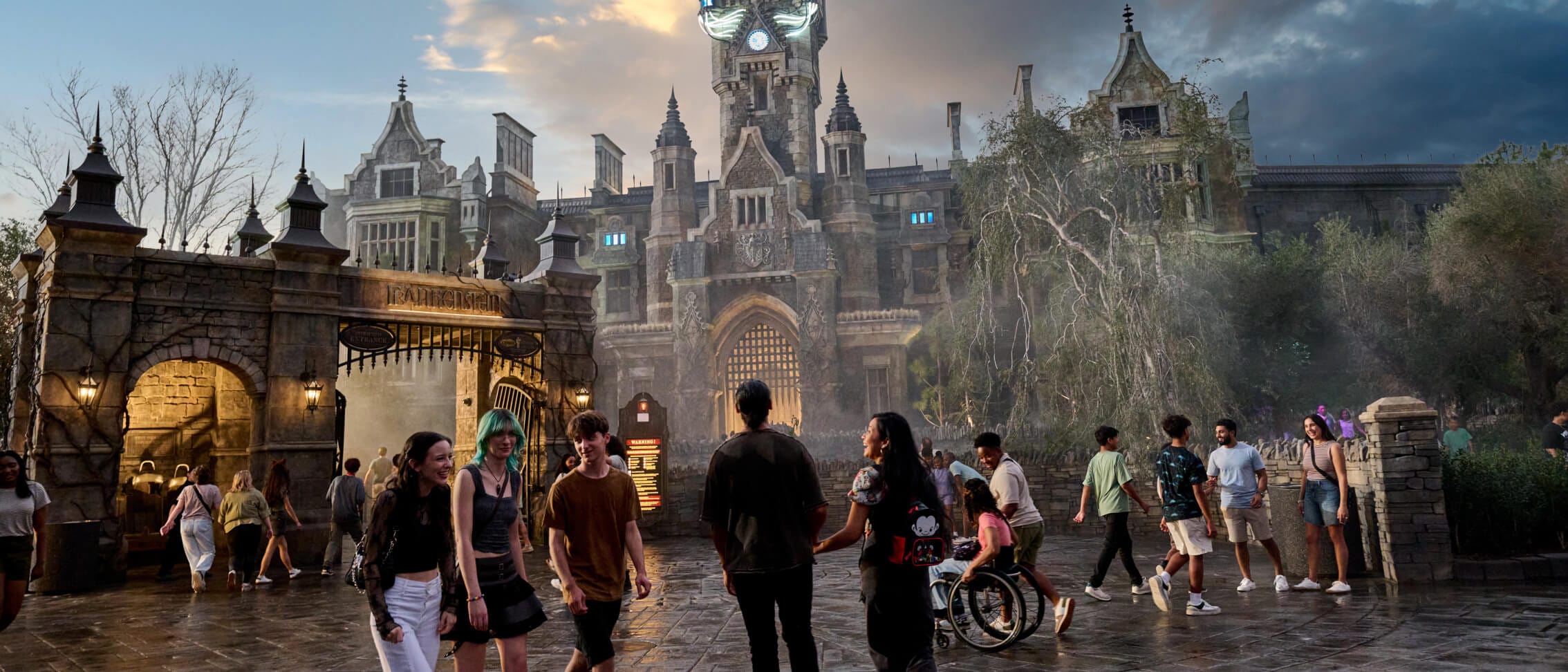 Visitantes do Dark Universe explorando as ruas de Darkmoor Village, com a entrada da Frankenstein Manor e Monsters Unchained: The Frankenstein Experiment ao fundo.