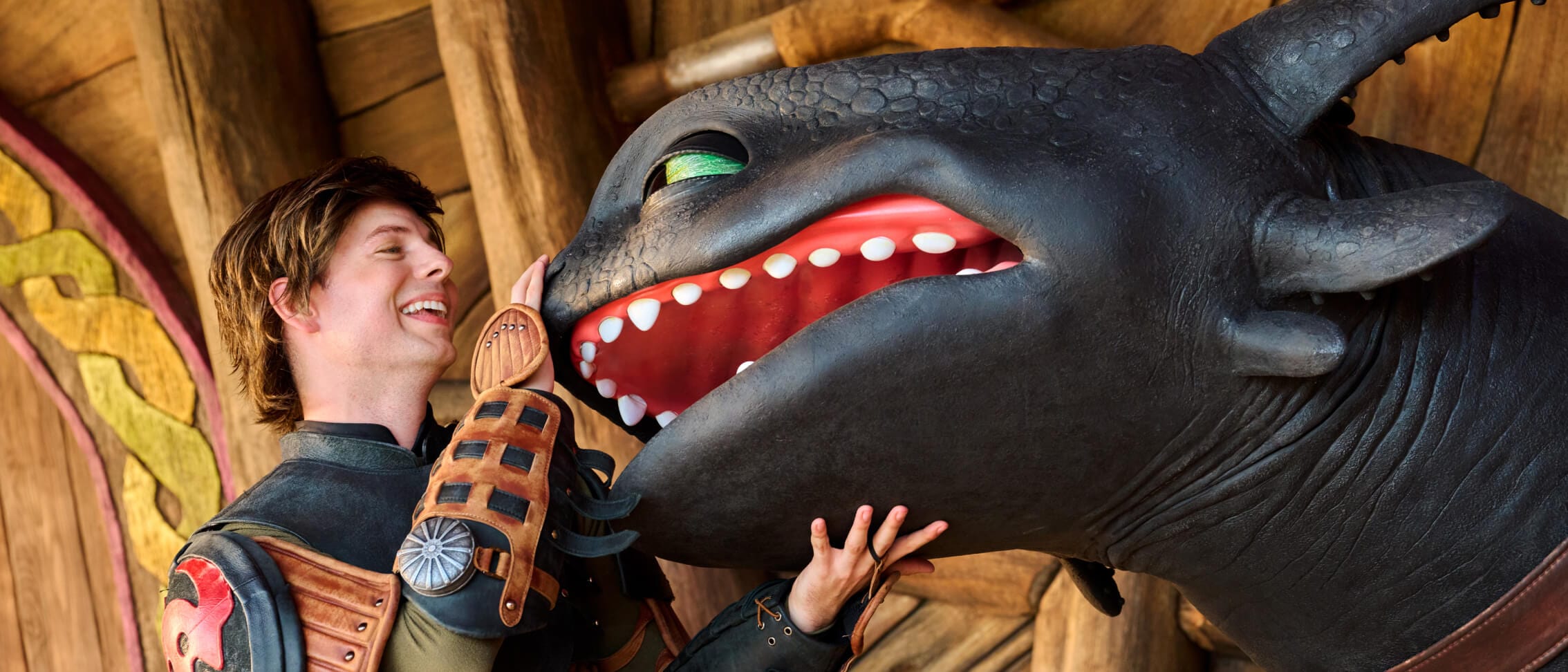 Soluço sorri para Banguela enquanto faz carinho em seu focinho em um encontro com personagens no How to Train Your Dragon - Isle of Berk.