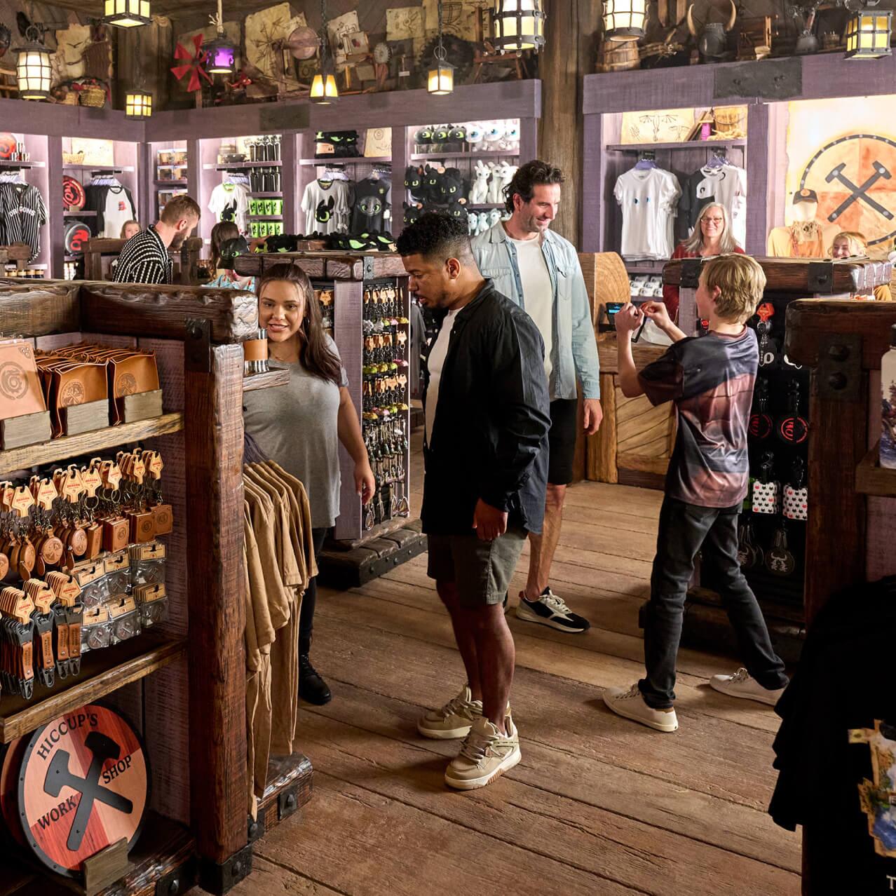 Visitantes olhando produtos temáticos de dragão na loja Viking Traders em How to Train Your Dragon – Isle of Berk.