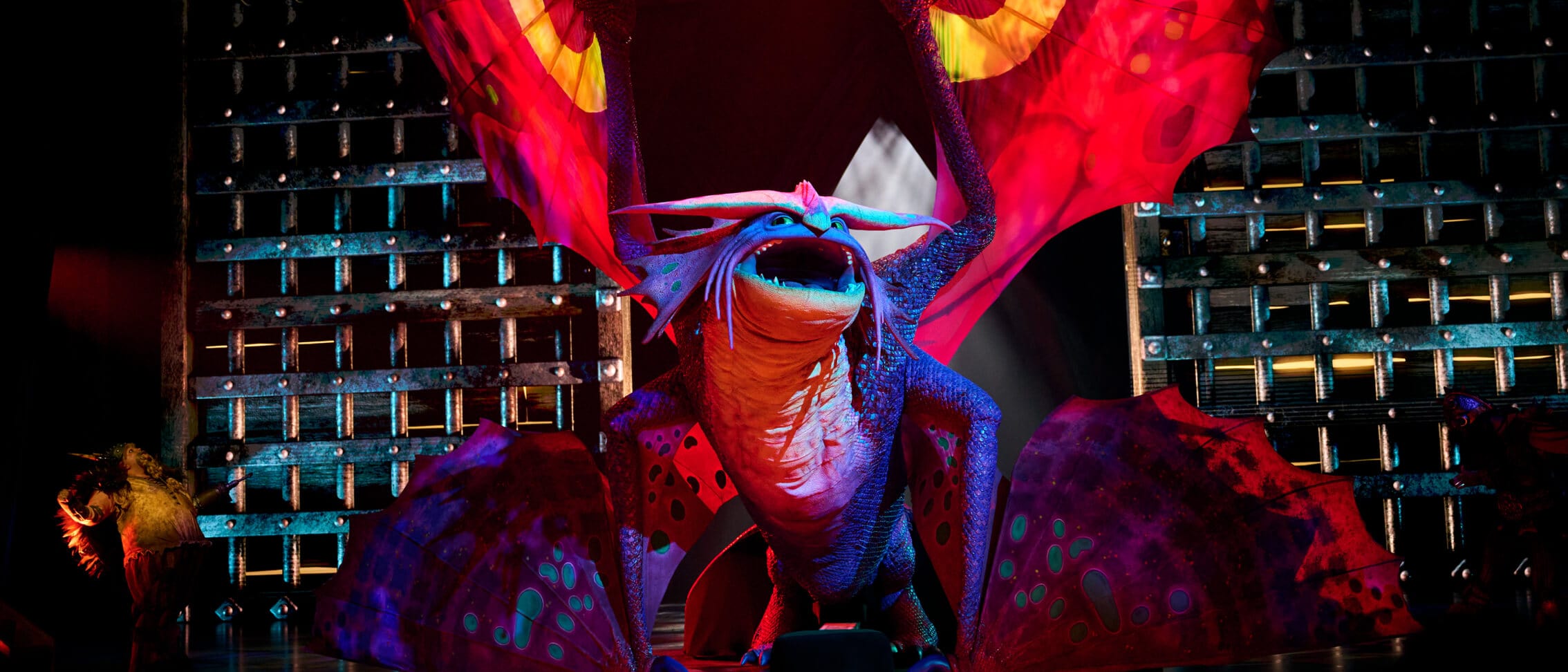 Um dragão Stormcutter no centro do palco abre suas asas bem alto e solta um rugido durante uma apresentação de The Untrainable Dragon no Universal Epic Universe.