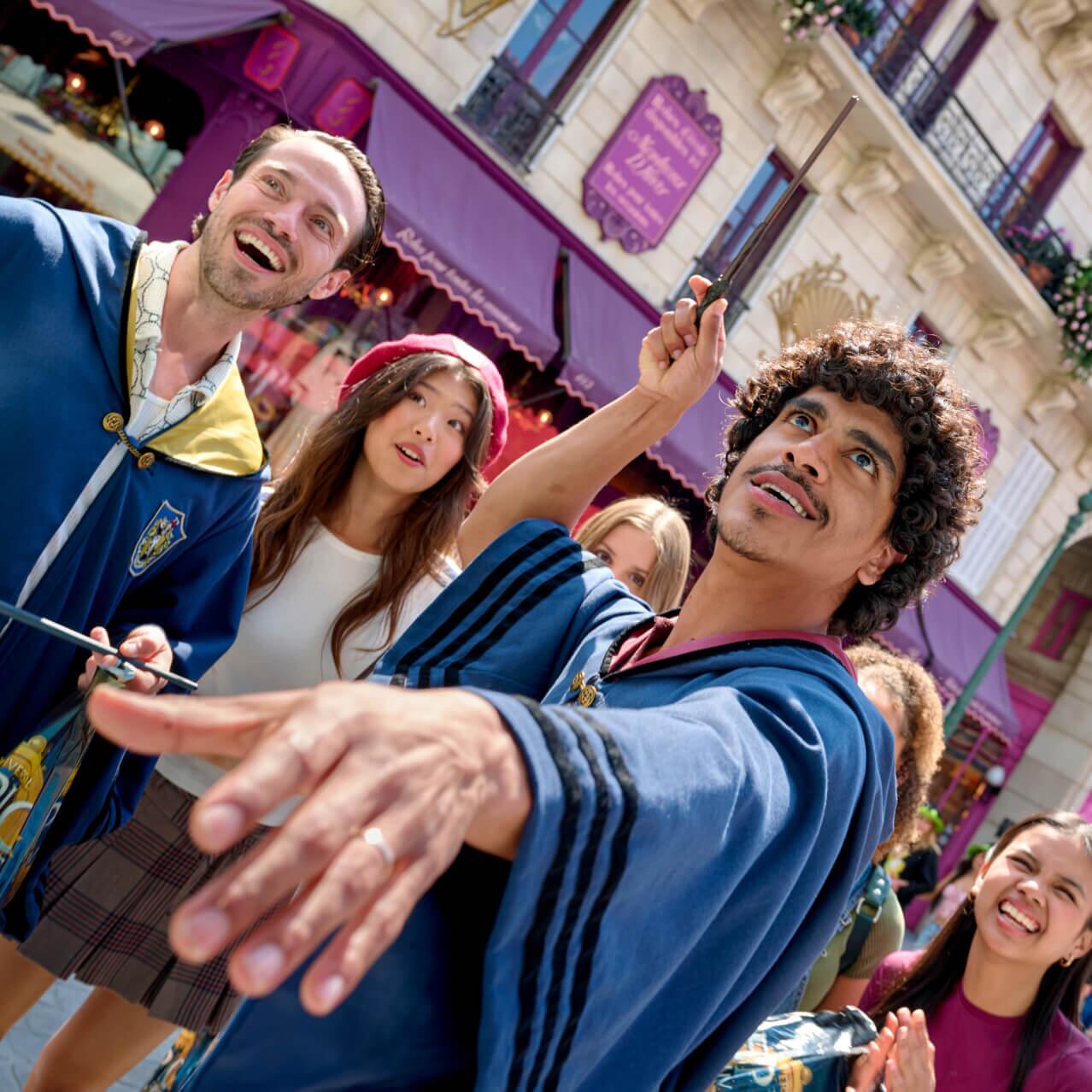 Friends wearing wizarding robes wave their wands in the air to cast spells in wizarding Paris.
