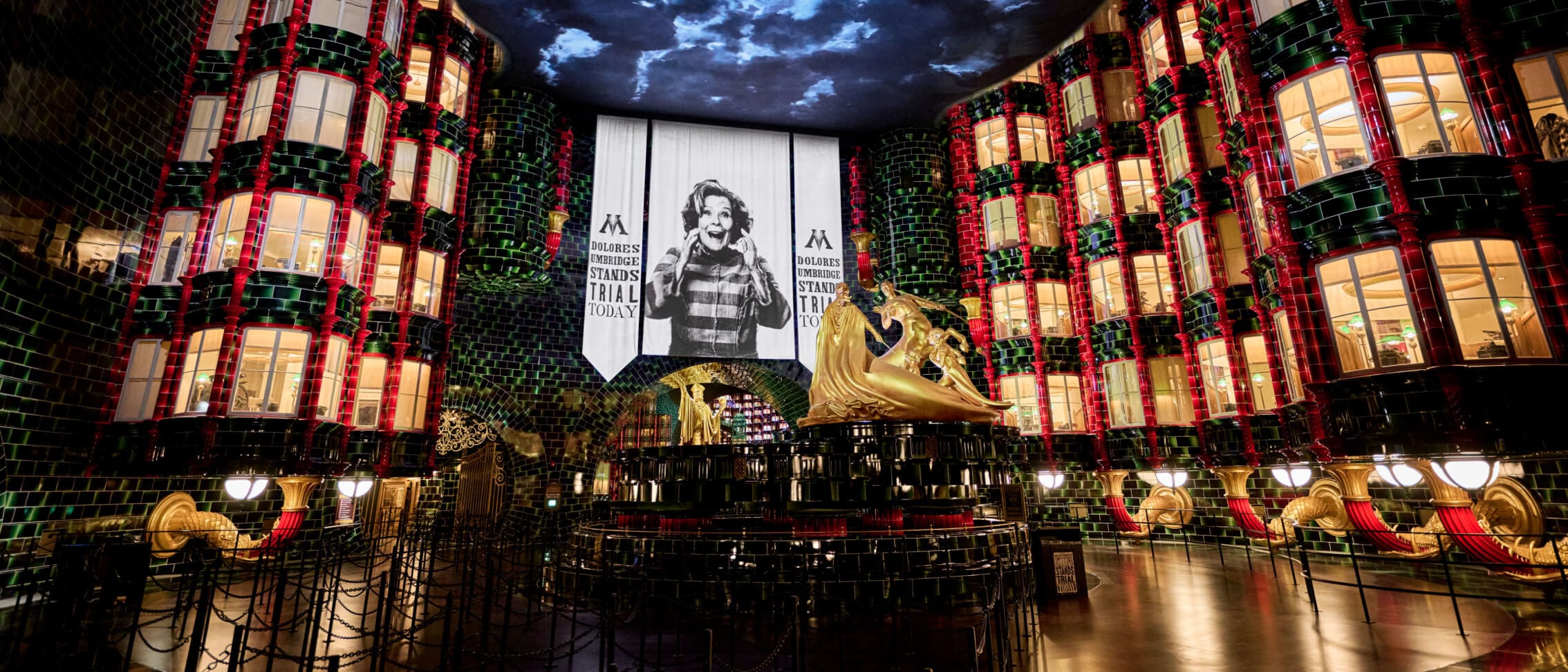 The queue of Harry Potter and the Battle at the Ministry™ ride opens to the Atrium with a large banner about the trial of Dolores Umbridge™.