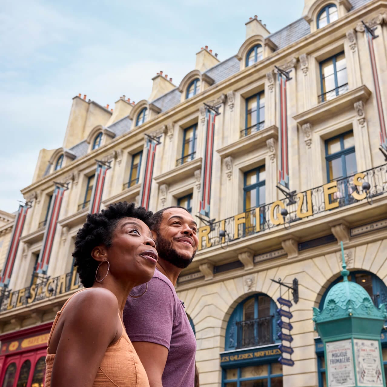 Um casal admirando a arquitetura da Paris bruxa em frente ao Les Galeries Mirifiques no The Wizarding World of Harry Potter™ — Ministry of Magic™.