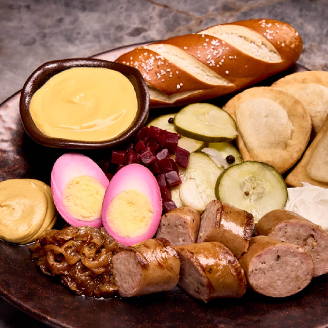 Alchemist's Platter of smoked sausage, potato & cheese pierogies, marinated beets, pickled egg, caramelized onions, warm pretzel, German mustard and cheese fondue served at Le Gobelet Noir.