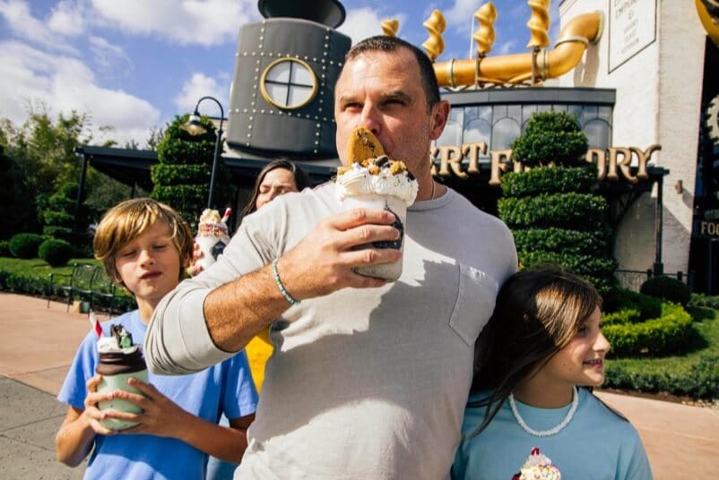 Dad with his two children enjoying a sweet treat outside of The Toothsome Chocolate Emporium & Savory Feast Kitchen.