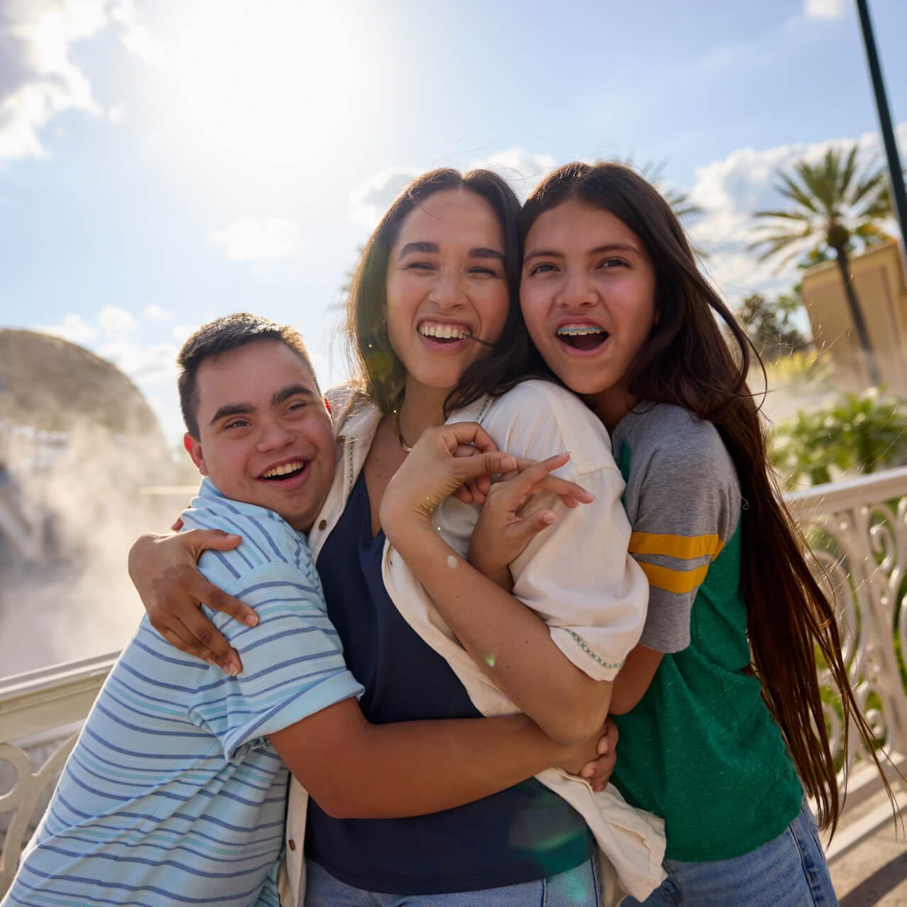 Uma família de três pessoas sorrindo e se abraçando enquanto posa para uma foto em frente ao icônico globo da Universal.