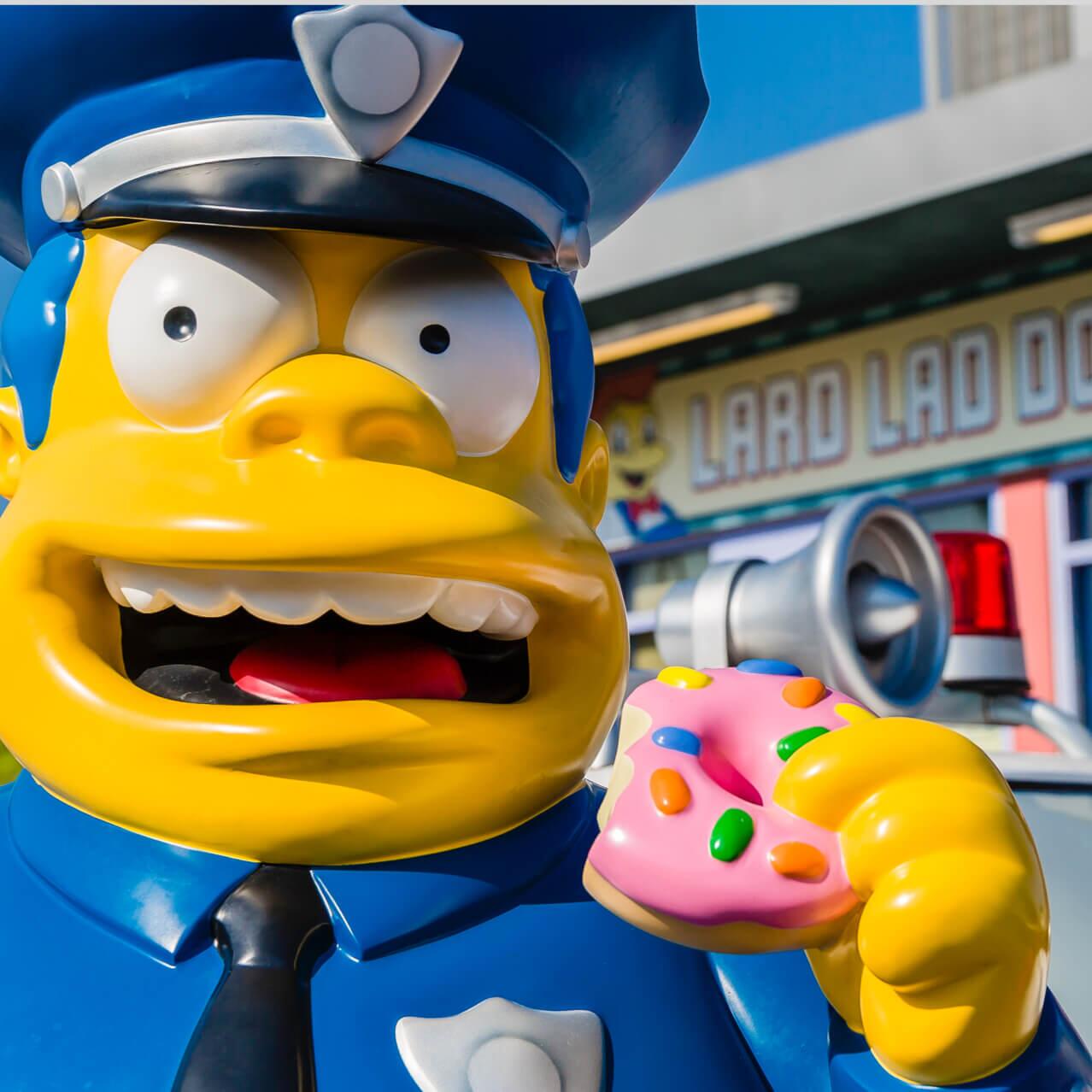 Uma estátua do personagem chefe de polícia Wiggum, dos Simpsons, do lado de fora da loja Lard Lad Donut, na área temática de Springfield do Universal Studios Orlando.