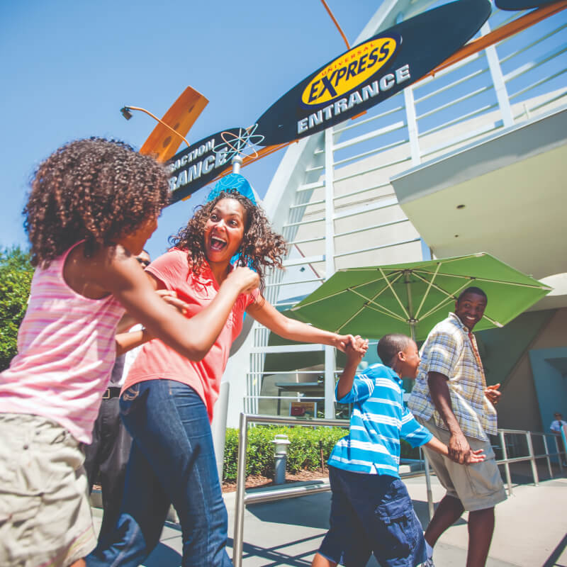 Uma família de quatro pessoas passa animada pela entrada Express de uma atração no Universal Studios Florida.