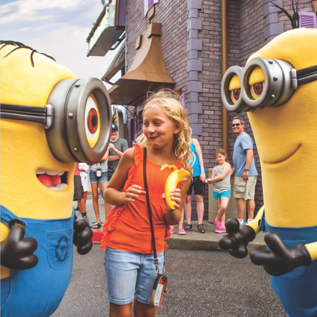 Garotinha sorrindo enquanto encontra dois Minions no passeio Meu Malvado Favorito 3D no Universal Orlando.