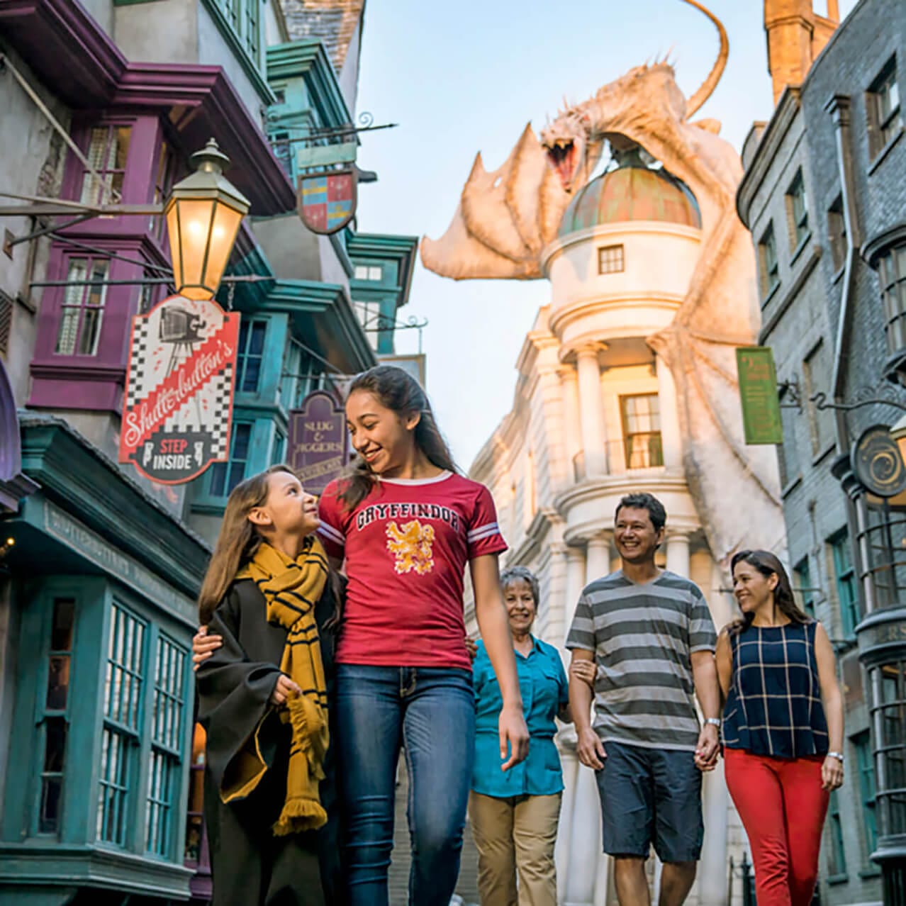 Família caminhando pelo Diagon Alley™ com um dragão ao fundo.