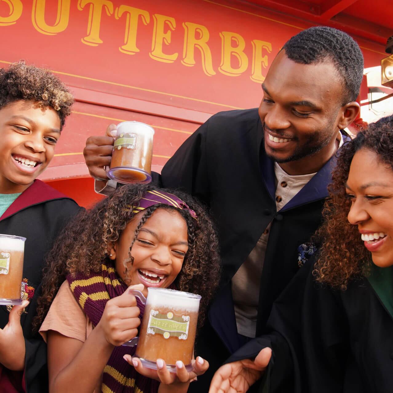 Uma família vestida com robes de Hogwarts™, sorrindo e desfrutando de uma frozen Butterbeer™ em Hogsmeade™.