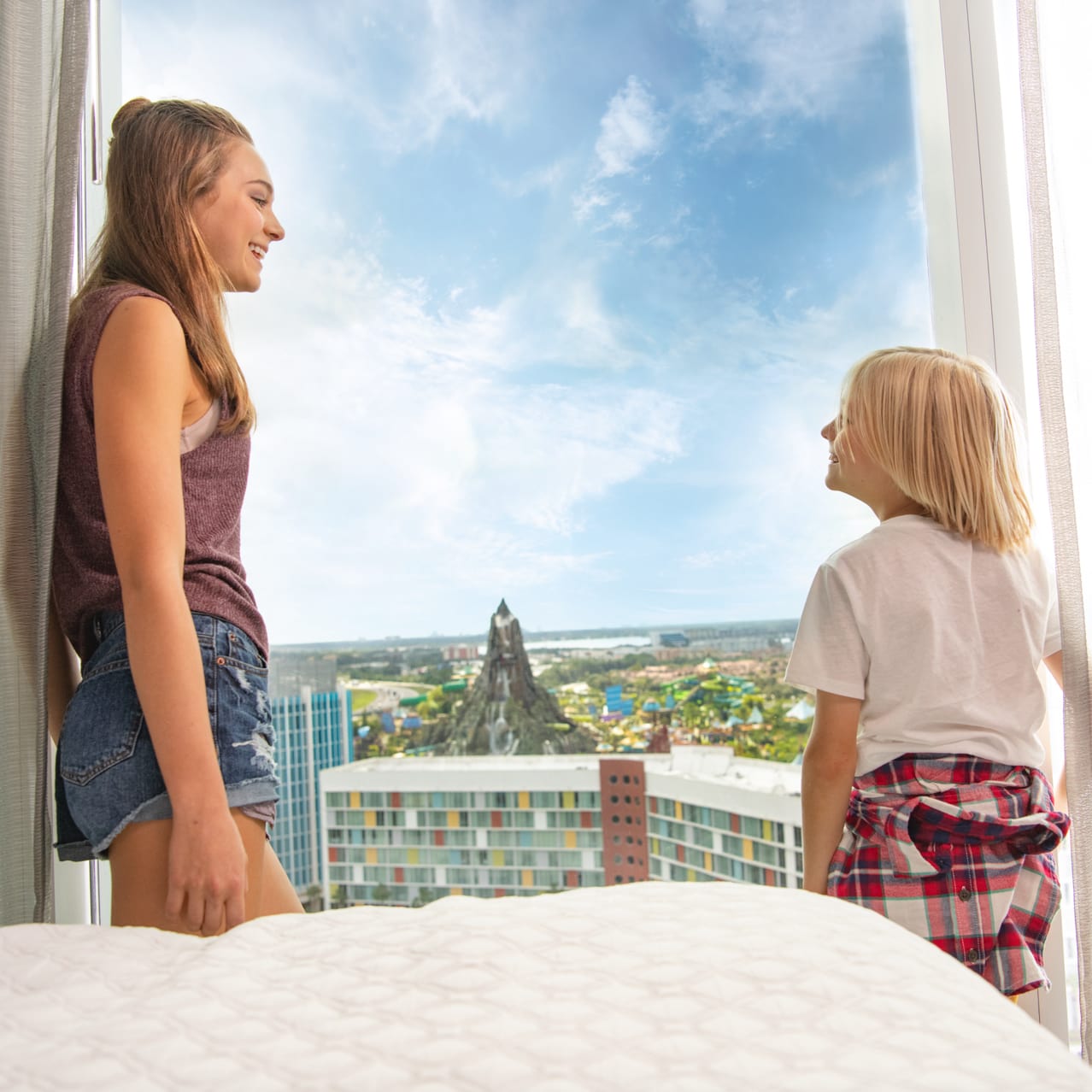 Kids looking out of a window at Universal's Aventura Hotel with Volcano Bay in the distance