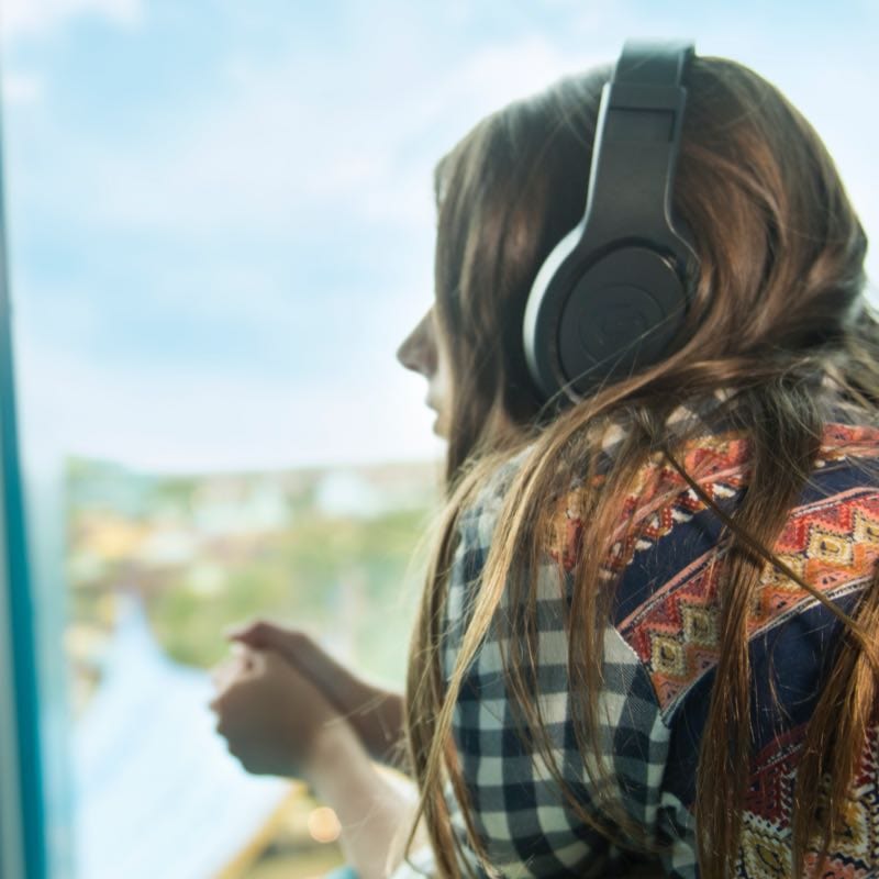 Teen looking out the window with headphones on
