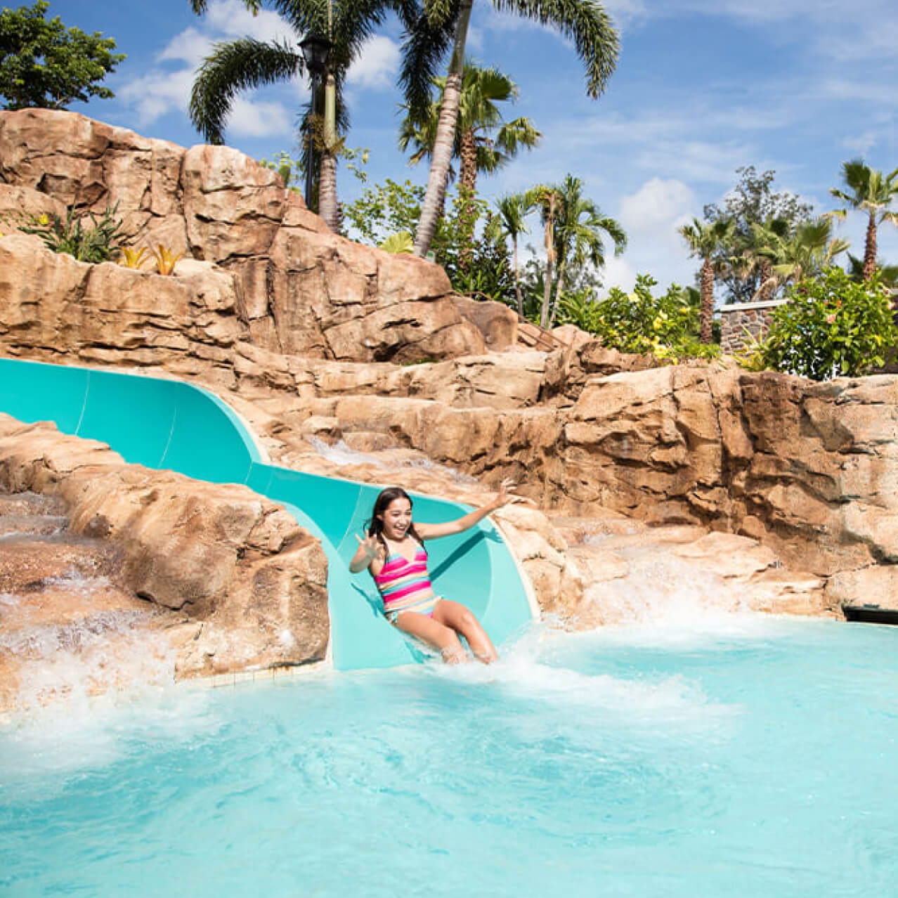 A girl sliding into the pool at Loews Sapphire Falls Resort