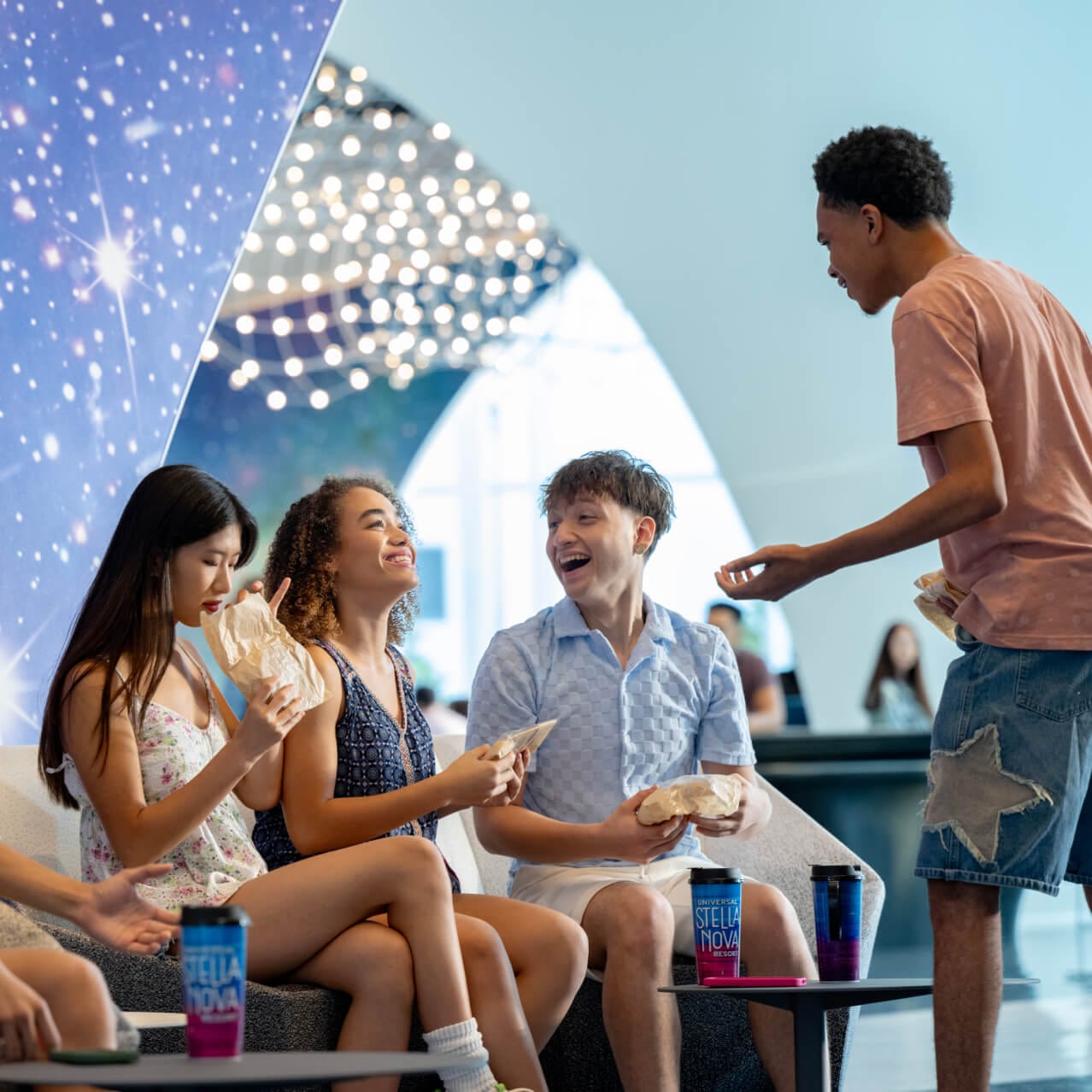 A group of friends sitting together inside of the interior lobby at the Universal Stella Nova Resort with stellar decor.