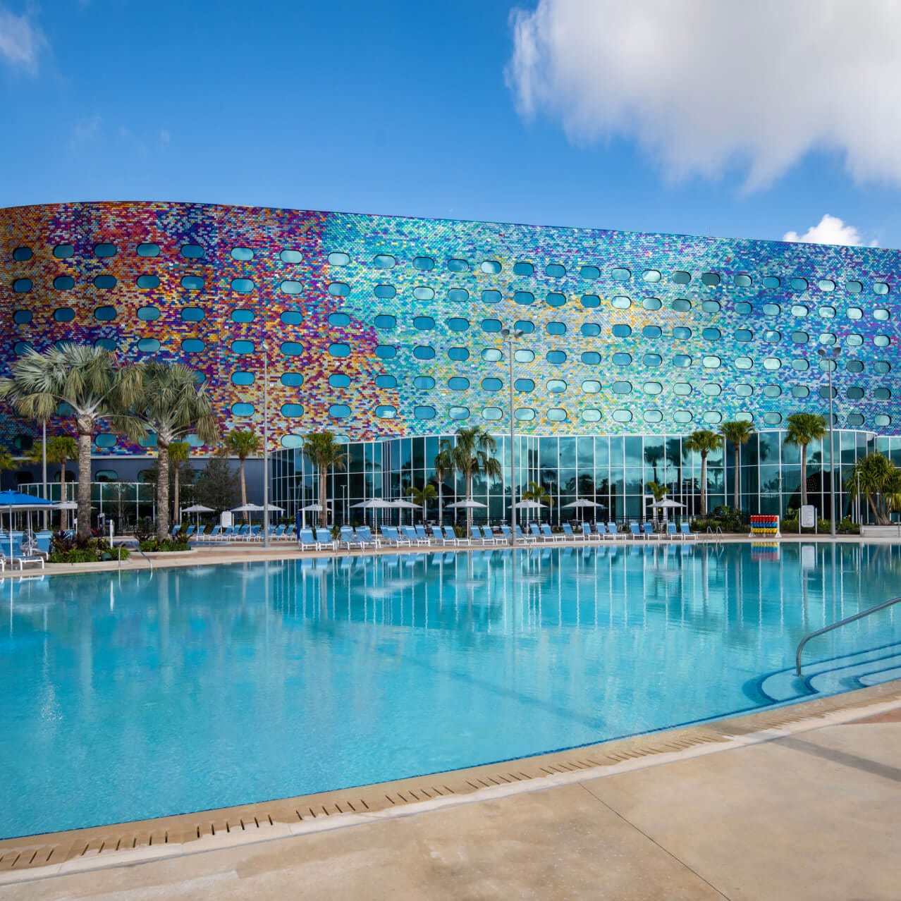 Universal Stella Nova Resort's pool and exterior shimmering in the sunlight with a rainbow of colors.