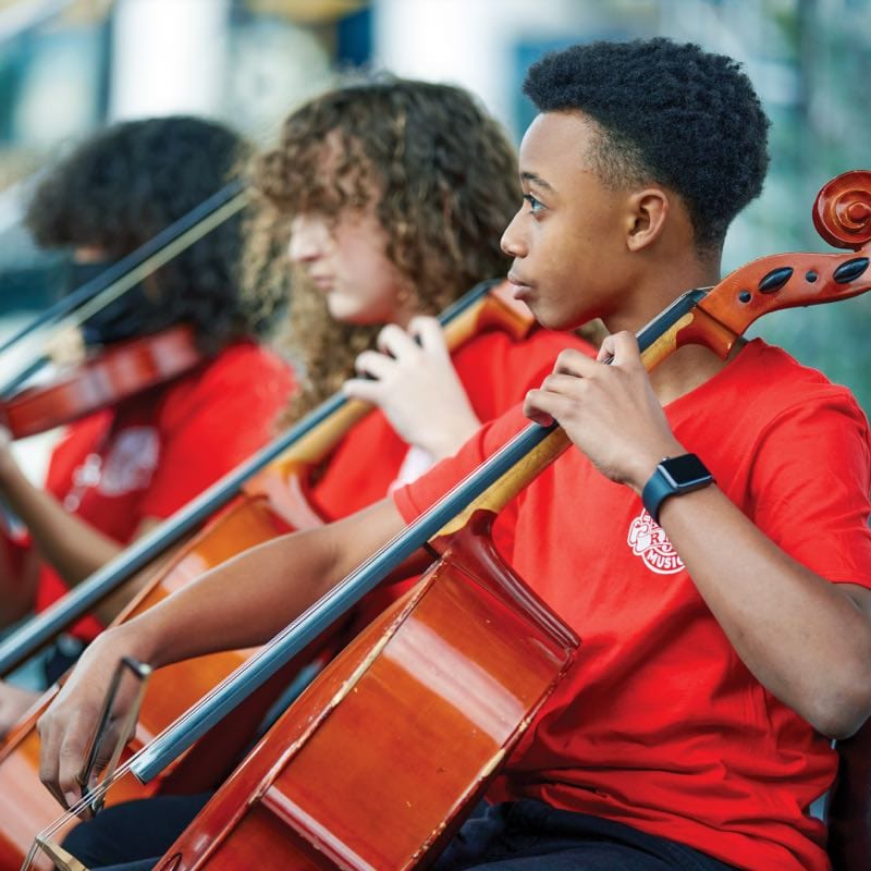 Kids playing cello in an orchestra performance