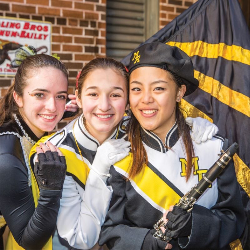 Three girls in a marching band posing for a picture