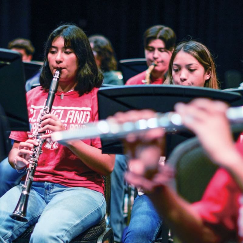A teenage girl playing a clarinet on a stage with other performers