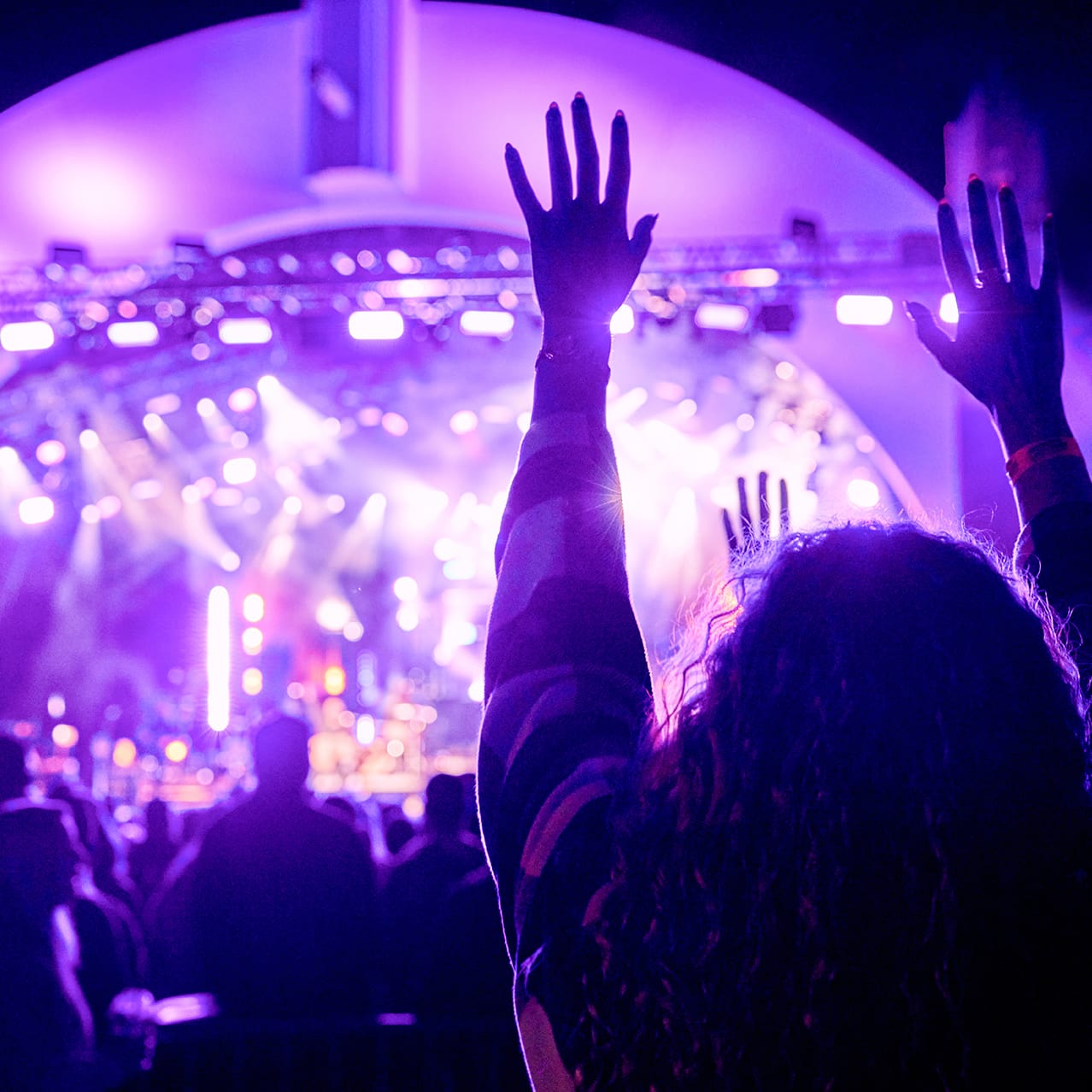 A woman has her hands raised at a Rock The Universe concert at Universal Studios Florida.