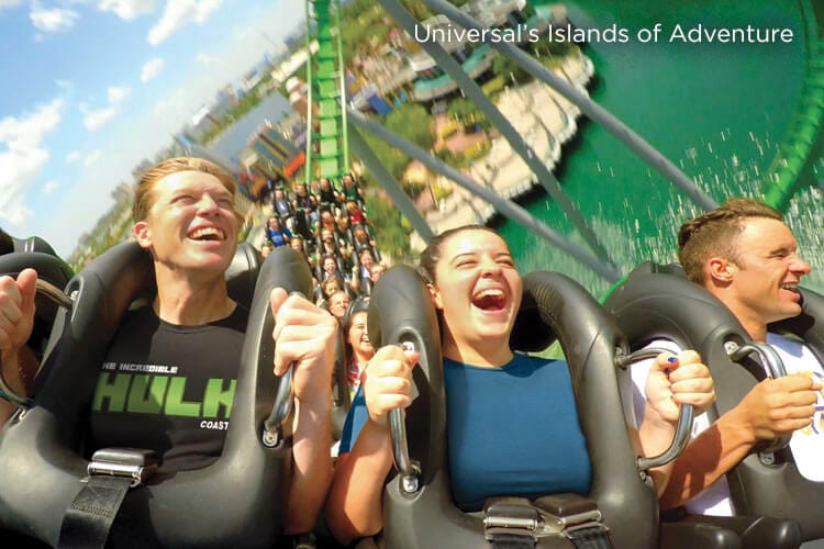 Four young adults scream and laugh while riding in the front row of The Incredible Hulk Coaster at Universal's Islands of Adventure in Orlando.