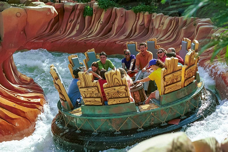 A large raft full of people barrels down the whitewater rapids of Popeye and Bluto's Bilge Rat Barges in the Toon Lagoon area of Universal's Islands of Adventure Orlando.