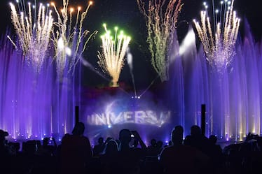 Fireworks and purple-lit water shoot toward the sky over a projection of the Universal globe during Universal Orlando's Cinematic Celebration show.