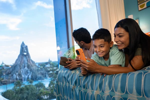 Family sitting on Cabana Bay Beach Resort Bed with Volcano Bay view.