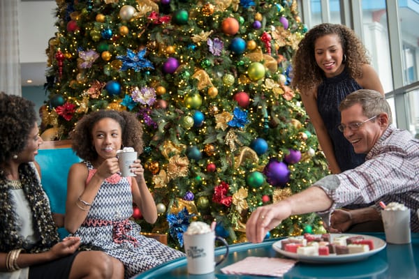 Family around a festive tree enjoying holiday themed treats at a Universal Orlando Resort