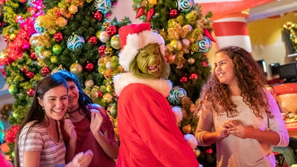 Guests meet and laugh with the Grinch dressed in a Santa costume during the holidays at Universal.