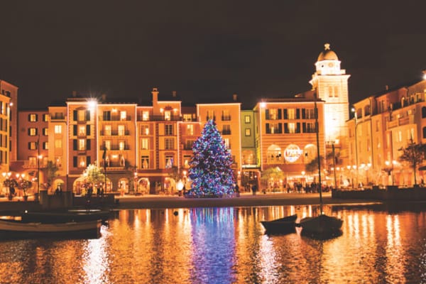 Image of Lowes Portofino Bay Hotel harbor with a holiday tree lit up at night.
