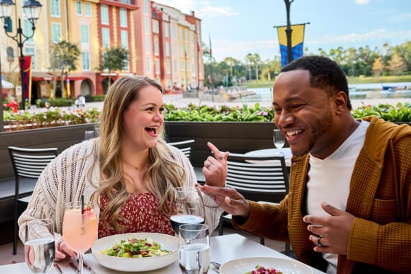 Two people sharing a meal and drinks at Trattoria del Porto at Loews Portofino Bay Hotel.