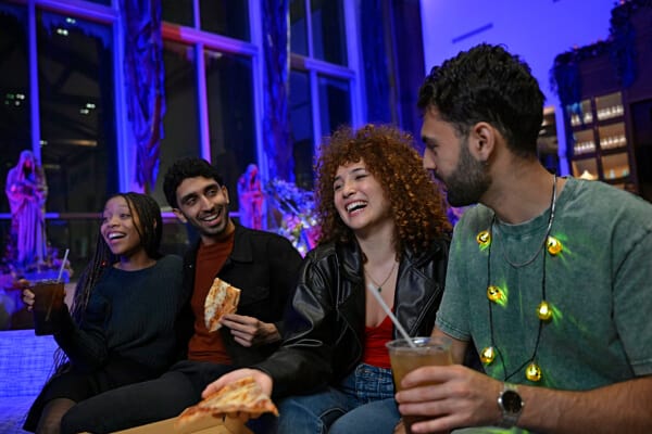 A group of four friends laughing and enjoying pizza at Cabana Bay's Swizzle Lounge during Halloween Horror Nights.