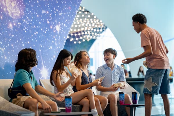 A group of friends sitting together inside of the interior lobby at the Universal Stella Nova Resort with stellar decor.