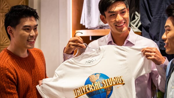 A guest sholds up a Universal Studios t-shirt while shopping with his friends inside a Universal Studios Store.