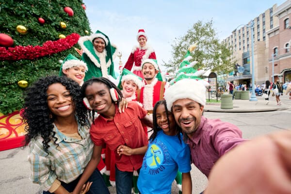 Family taking selfie in front of giant Christmas tree in New York at Universal Studios Florida.