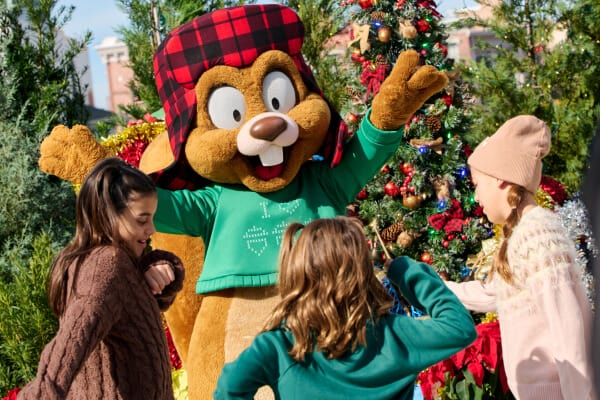 Earl the Squirrel dancing with three girls around a christmas tree